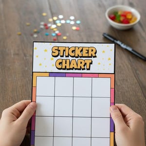 Könnte beinhalten: Ein farbenfrohes Sticker-Chart mit den Worten "STICKER CHART" in Orange und Gelb. Das Chart hat ein weißes Raster für Aufkleber und einen Rand mit orangefarbenen, rosa- und lilafarbenen Akzenten. Ein schwarzer Marker und eine kleine Schale mit Süßigkeiten sind ebenfalls zu sehen.
