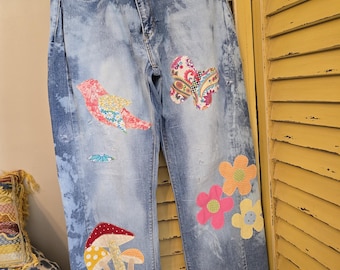 Vaqueros bohemios de mujer, confeccionados con materiales reciclados y con apliques florales, inspirados en Magnolia, Rare Bird y Tmyers. Talla 16 M.