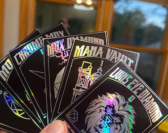 May include: A hand holding a fan of black cards with holographic foil accents. Each card features unique designs and text, including "Chrome Mox," "Mana Vault," and "Lion's Eye Diamond." The cards are labeled as "Artifacts."