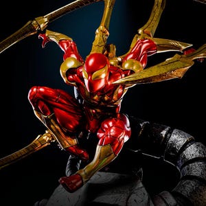 May include: A red and gold Spider-Man action figure in a crouching pose. The figure has multiple golden mechanical arms extending from its back. The figure is highly detailed with a metallic finish, set against a dark background.