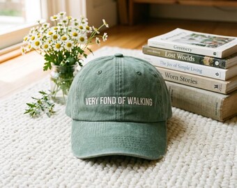 Gorra bordada con la frase "Orgullo y prejuicio" y otra similar a una gorra de béisbol con la cita "Me encanta caminar".