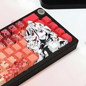 Puede incluir: Un teclado mecánico negro con teclas personalizadas. Las teclas presentan un degradado de tonos rosa y naranja, con diseños florales y de personajes de estilo anime. También hay teclas rojas, y el teclado tiene una perilla plateada.