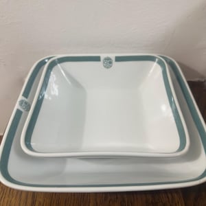 Puede incluir: Una taza de cerámica blanca con un asa negra y el texto "But First, Coffee" en negrita negra. La taza está sobre una superficie de madera. La taza mide 10 cm de alto.