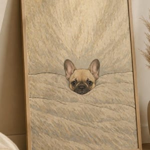 Puede incluir: Impresión enmarcada de un bulldog francés color leonado asomando de un fondo beige texturizado. La expresión atenta del perro y los tonos neutros crean una estética artística y acogedora. El marco es de color madera clara.