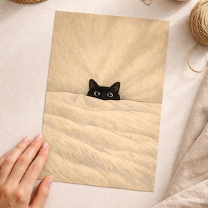 Puede incluir: Una ilustraci&oacute;n caprichosa presenta un gato negro asom&aacute;ndose por encima de una manta beige. Los ojos del gato son grandes y curiosos. La obra de arte est&aacute; sobre papel texturizado, con una taza de caf&eacute; y otros elementos decorativos en el fondo.