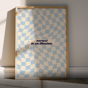 May include: A framed poster with a wavy checkered pattern in light blue and cream colors. The text "normal is an illusion" is centered on the poster in a dark blue font. The poster is leaning against a white wall.