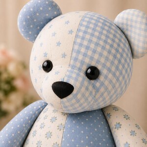May include: A stuffed teddy bear constructed from patchwork fabric panels in shades of light blue and white. The bear features a mix of patterns including small stars, gingham checks, polka dots, and floral prints, with black plastic eyes and nose.