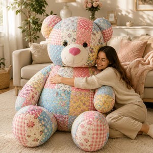 May include: A large, oversized teddy bear constructed from a patchwork of various floral and gingham patterned fabrics in shades of pink, blue, and yellow. The bear features a bright pink nose and two dark, round button eyes.