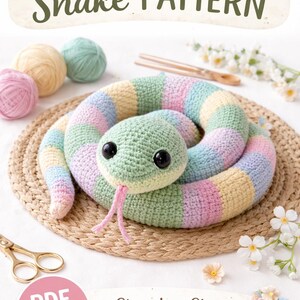 Pode incluir: Um padrão de crochê de cobra com instruções passo a passo. A cobra é em cores pastel verde, amarelo, rosa e azul. A imagem inclui novelos de lã, tesouras e o texto "CROCHET Snake PATTERN".