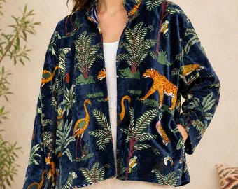 Puede incluir: Una chaqueta de terciopelo azul marino con un estampado vibrante de temática selvática que incluye leopardos, flamencos, monos y hojas de palmera tropicales. La chaqueta tiene cuello alzado, mangas largas y dos bolsillos laterales.
