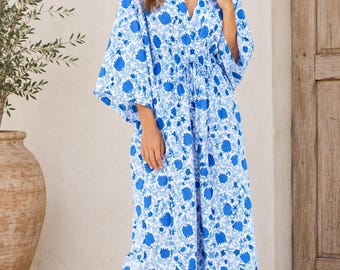 Puede incluir: Un vestido largo hasta los pies con un estampado floral en azul y blanco. La prenda presenta un escote en V profundo, mangas anchas estilo kimono y un cordón ajustable en la cintura. La tela tiene una caída suelta y fluida.