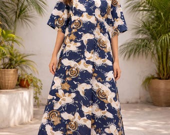 Könnte beinhalten: Ein marineblaues Maxikleid mit V-Ausschnitt und kurzen Ärmeln. Das Kleid hat ein sich wiederholendes Muster aus weißen Kranichen und goldenen Kreisdesigns. Das Model trägt braune Sandalen. Das Kleid ist für Freizeitkleidung geeignet.