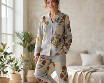Puede incluir: Un conjunto de pijama de dos piezas que incluye una camisa de manga larga con botones y un pantalón a juego. La tela tiene un patrón de cuadros vichy en azul y blanco con un estampado de formas circulares marrones y hojas verdes.
