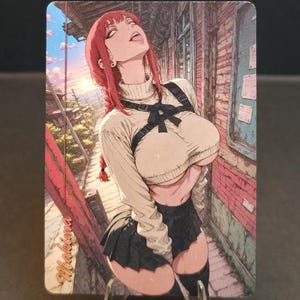 May include: Anime-style art print featuring a woman with red hair in a white sweater, black skirt, and thigh-high socks. The artwork is set against a backdrop of a city street with brick walls and a blue window. The print is displayed on a clear stand.