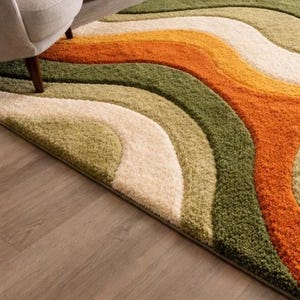 Abstract wave shaggy rug in olive green, orange, and cream colors placed in a modern living room with beige sofa and large windows