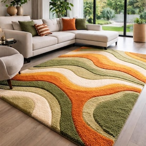 Abstract wave shaggy rug in olive green, orange, and cream colors placed in a modern living room with beige sofa and large windows