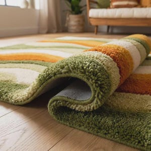 Abstract wave shaggy rug in olive green, orange, and cream colors placed in a modern living room with beige sofa and large windows