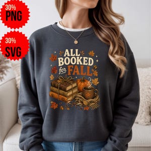 Peut inclure: Un sweat-shirt gris anthracite à col rond avec une impression graphique portant le texte ALL BOOKED for FALL. Le motif comprend une pile de trois livres attachés avec une ficelle, une citrouille, une tasse fumante et des feuilles d'automne.