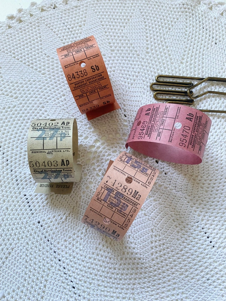 May include: Close-up of four vintage bus tickets from different cities in the United Kingdom. The tickets are in various colors, including pink, brown, and white. The tickets have text that includes the city name, the date, and the fare.