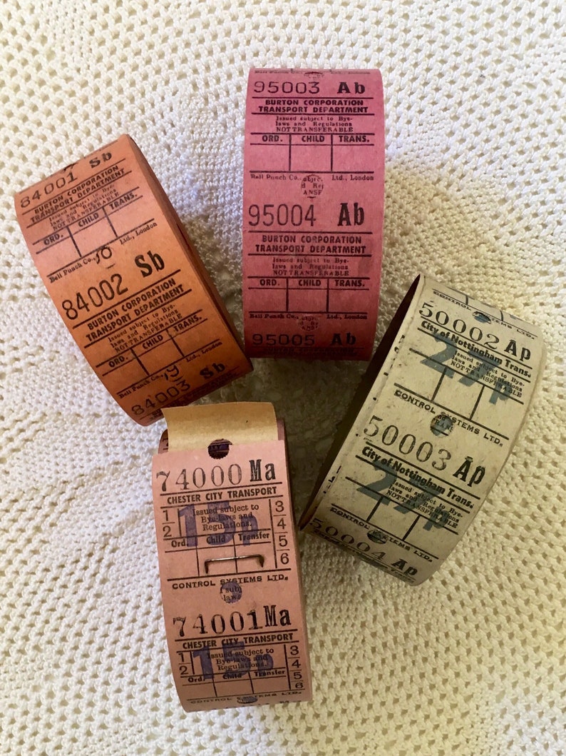 May include: A collection of vintage bus tickets from different cities in the United Kingdom. The tickets are made of paper and have a variety of colors, including red, brown, and white. The tickets are all rolled up and have a worn, vintage look.