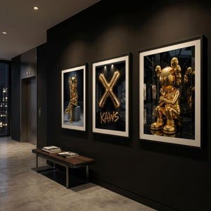 May include: Three framed art prints on a black wall. The prints feature gold sculptures and a gold balloon "X" with "KAWS" text. A bench and elevator are also visible in the hallway.