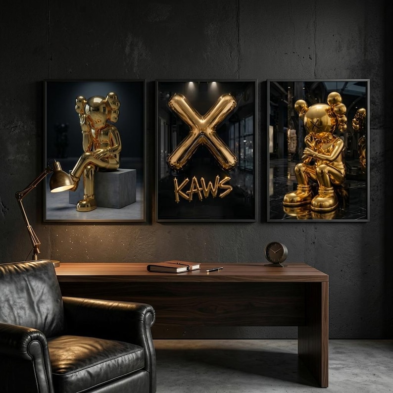May include: Three framed art prints showcasing gold KAWS figures and a gold balloon 'X' with the word 'KAWS'. The prints are above a dark wood desk with a black leather chair and a gold desk lamp.