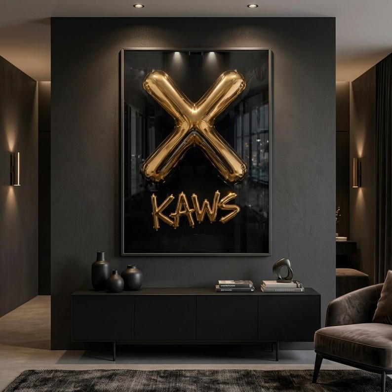 May include: A framed artwork featuring a gold balloon sculpture in the shape of an X, with the word "KAWS" below. The artwork is set against a dark background, mounted above a black cabinet with decorative vases and books.