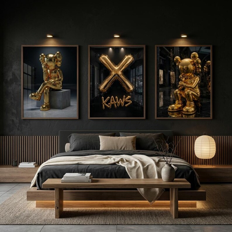 May include: Three framed art prints showcasing gold KAWS figures and a gold "X" balloon design against a dark backdrop. The prints are displayed above a bed with a wooden frame and a neutral-toned rug.