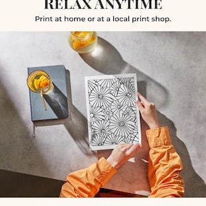 May include: A coloring page with a black and white geometric design is held by a person wearing an orange shirt. The image includes a glass of orange-infused water and a blue notebook. Text reads "COLOUR AND RELAX ANYTIME" and "Print at home or at a local print shop."