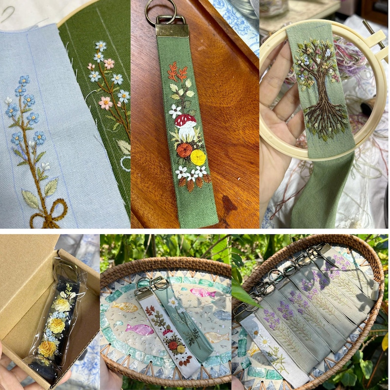 May include: A collection of fabric keychains featuring intricate floral and botanical embroidery. Designs include a tree with roots, mushrooms, and various wildflowers on green and blue fabric strips, finished with metal key rings and hardware.