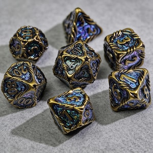 May include: A collection of seven polyhedral dice with a metallic gold finish and blue and purple iridescent accents. The dice are designed with intricate patterns and numbers, suitable for tabletop gaming.
