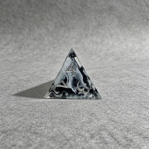 May include: A clear, triangular die with a black and white marbled interior. The number "4" is prominently displayed on the top face, with other numbers visible on the sides. The die is designed for tabletop games.