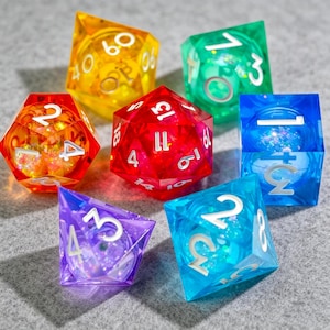 Op de afbeelding: Zeven veelkleurige polyhedrale dobbelstenen met witte cijfers en glitter. De dobbelstenen zijn transparant en verkrijgbaar in geel, rood, groen, blauw, paars en turquoise. Deze dobbelstenen zijn voor tabletop games.