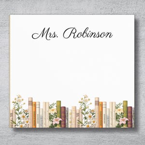 May include: White notepad with the name "Mrs. Robinson" in elegant script. The bottom border features a row of vintage books and floral accents in shades of cream, green, and pink.