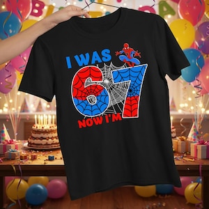 Könnte beinhalten: Ein schwarzes Kurzarm-T-Shirt mit einem Grafikdruck, der den Text I WAS 67 NOW I'M, ein Spinnennetz-Muster und eine rot-blaue Superheldenfigur zeigt. Die Zahl 67 ist in einer großen Schrift mit einem rot-blauen Spinnennetz-Design dargestellt.