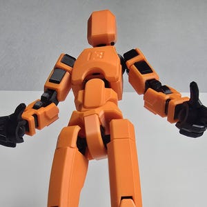 Heroic low-angle perspective of the 11-inch Titan Dummy 13 in Vibrant Orange. Highlights the massive scale, robust engineering, and industrial construction.