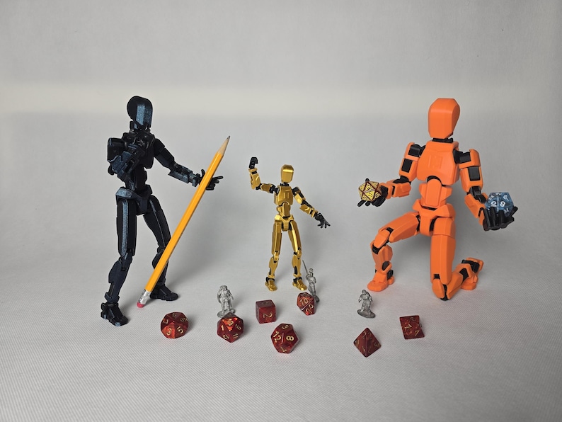 Three articulated figures in dynamic action poses with Dungeons & Dragons dice and a pencil on a clean white background. Showcases the 5.25-inch scale and interactive desk fidget capabilities.