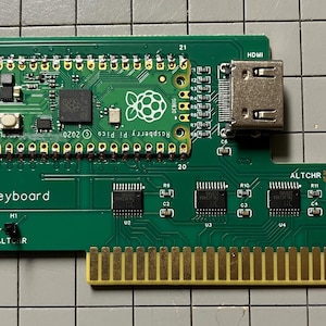 May include: A green circuit board with a Raspberry Pi Pico microcontroller, an HDMI port, and a USB-C port. The board has a text label that says "<-Keyboard" and "Raspberry Pi Pico 2020".