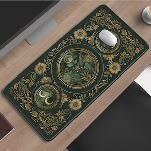 Puede incluir: Una alfombrilla de ratón rectangular verde oscuro con un diseño floral y celestial. La alfombrilla presenta detalles florales y de hojas doradas, junto con diseños circulares con lunas y elementos celestiales. Un ratón blanco está encima.
