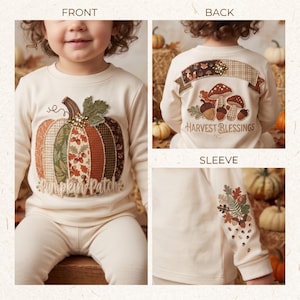 May include: A cream-colored long-sleeve shirt and pants set. The front features a patchwork pumpkin with the text "Pumpkin Patch". The back displays mushrooms, acorns, and the text "Harvest Blessings". The sleeve has a botanical acorn and leaf design.
