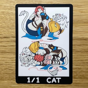 May include: A rectangular trading card featuring two white lion characters with white manes, wearing blue and gold armour, each playing with a red ball of yarn. The card has a black border and the text 1/1 CAT printed in white at the bottom.
