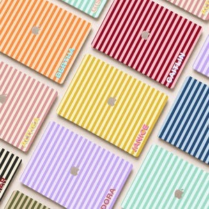 May include: A collection of laptop skins featuring vertical stripes in various colors including orange, red, yellow, purple, and mint green. Each skin displays a central Apple logo cutout and a personalized name printed in a bold, block font.