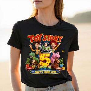May include: A black t-shirt featuring a colorful Toy Story graphic with characters Woody, Buzz Lightyear, Jessie, Rex, Slinky Dog, Hamm, Bullseye, and green soldiers. A large yellow number 5 is centered, with the text TOY STORY and ANDY'S ROOM 2026.