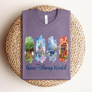 May include: A purple t-shirt featuring watercolor illustrations of iconic Walt Disney World landmarks: the Tree of Life, Cinderella Castle, Spaceship Earth, and the Tower of Terror. The words "Walt Disney World" are written in a script font below the images.
