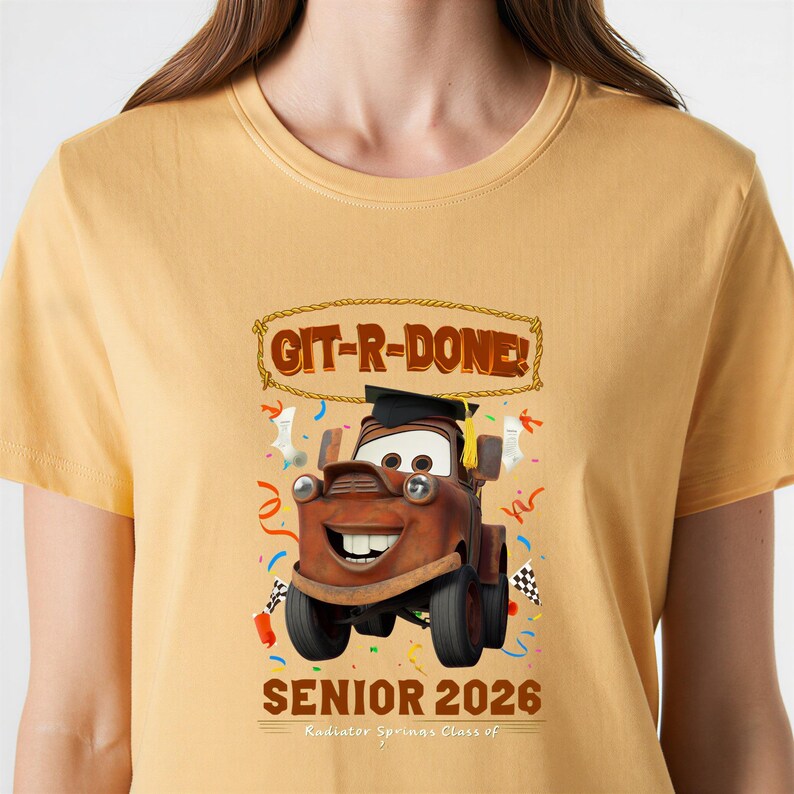Op de afbeelding: Mosterdgeel T-shirt met een cartoonafbeelding van Takel uit de film Cars, met een afstudeerhoed. De tekst "GIT-R-DONE!" staat boven Takel en "SENIOR 2026" staat eronder. Radiator Springs Class of is ook gedrukt.