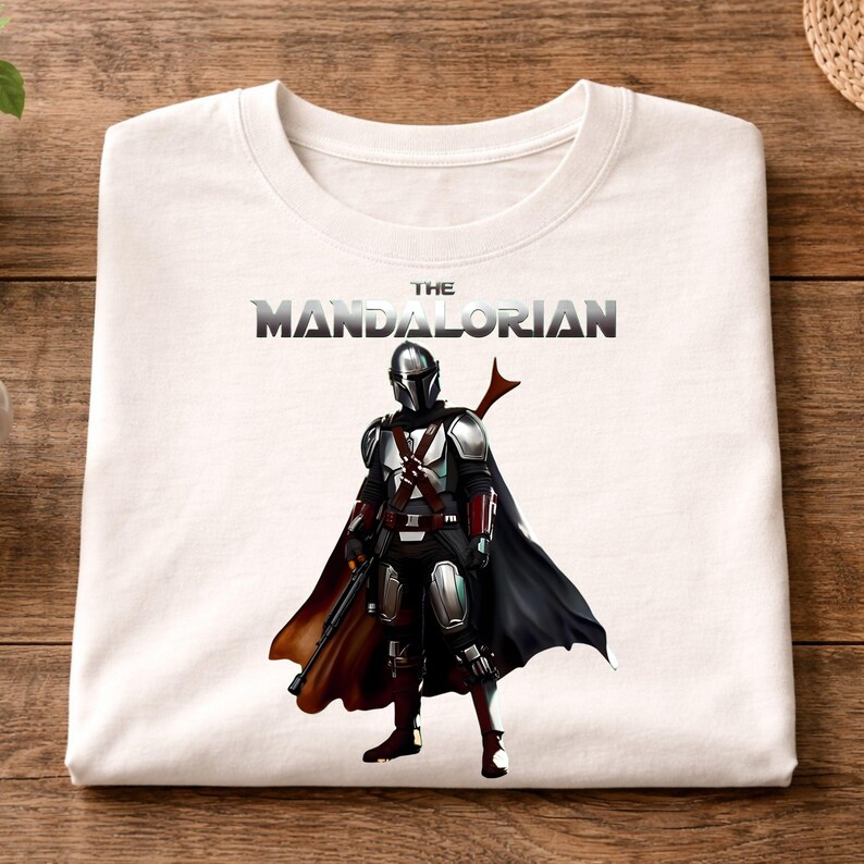 Op de afbeelding: Witte crewneck sweatshirt met een afbeelding van The Mandalorian uit de Star Wars-serie. De afbeelding toont het personage in volledige bepantsering met een zwarte cape en de tekst "THE MANDALORIAN" boven het personage.
