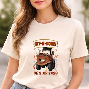 Op de afbeelding: Beige T-shirt met een cartoonafbeelding van Takel uit de film Cars, met een afstudeerhoed. De tekst "GIT-R-DONE!" staat boven de afbeelding en "SENIOR 2026" eronder. Kleurrijke confetti omringt de afbeelding.