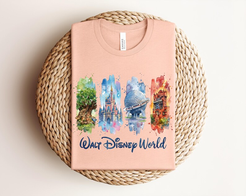 May include: A peach-colored t-shirt featuring a watercolor design of iconic Walt Disney World landmarks. The design includes the Tree of Life, Cinderella Castle, Spaceship Earth, and the Tower of Terror, with "Walt Disney World" written below.