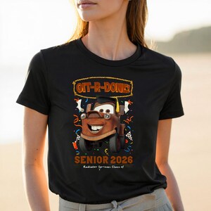 Op de afbeelding: Zwart T-shirt met een cartoonafbeelding van Takel uit de film Cars, met een afstudeerhoed. Het shirt bevat de tekst "Git-R-Done!" en "Senior 2026, Radiator Springs Class of".