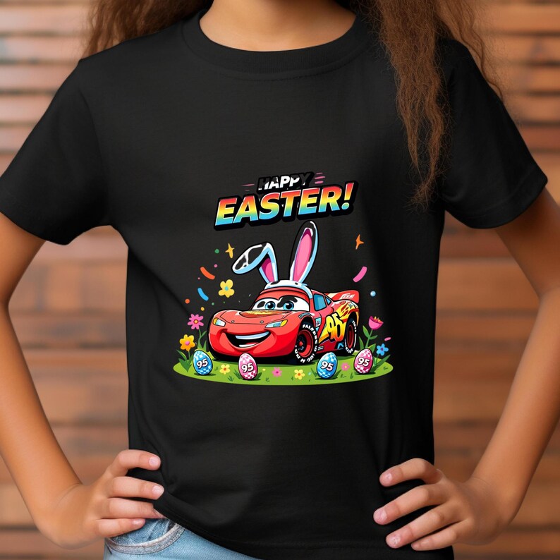 Puede incluir: Camiseta negra con una imagen de dibujos animados de un coche de carreras rojo con orejas de conejo, rodeado de huevos de Pascua y flores. El texto "HAPPY EASTER!" est&aacute; encima del coche en letras coloridas. Un dise&ntilde;o divertido y festivo para la Pascua.